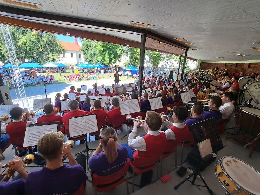 Pohled zezadu na orchestr při venkovním festivalovém vystoupení v roce 2022